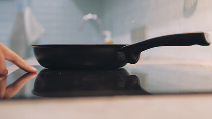 Man puts a frying pan on the induction panel