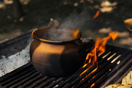 Clay pot releasing smoke on a grill with fire 