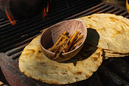 Container with cinnamon on some yellow corn tostadas above a grill 