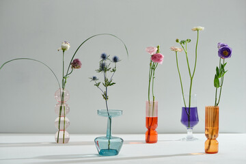 A closeup shot of four glass vases with different wildflowers