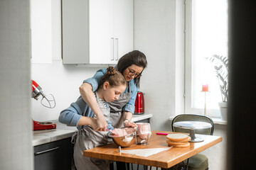 The family enthusiastically prepares a cake in the kitchen