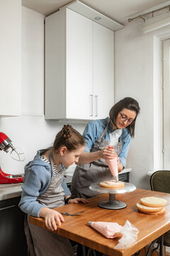 Mother teaches daughter to cook cake in the kitchen together