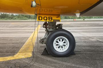 The airplane wheels are blocked by a chock block. Rubber wheel chock under the aircraft's wheels.