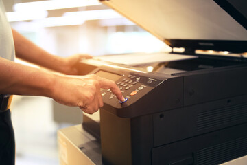 Copiers printer, Close up hand office man press copy button on panel to using the copier or photocopier machine for scanning document printing a sheet paper and xerox photocopy. - obrazy, fototapety, plakaty