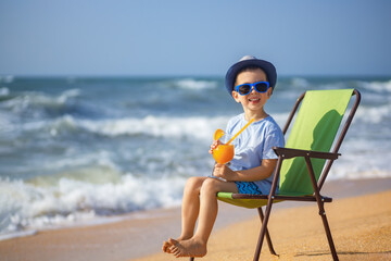 happy little boy drinking juice on sea beach