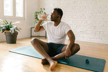Athlete male drinking water from the bottle indoors