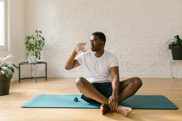 Athlete male drinking water from the bottle indoors