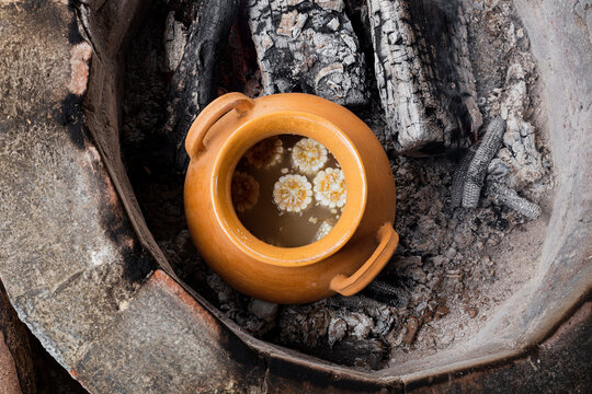 Top view of a clay pot with pieces of corn inside