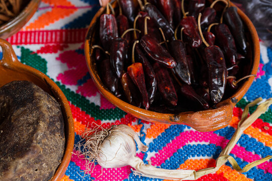 Clay containers with dried chili peppers and piloncillo or cane 