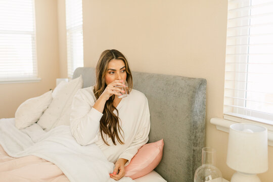 Woman drinking a glass of water from bed