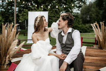 The bride in a rustic wedding dress smiles and touches the groom