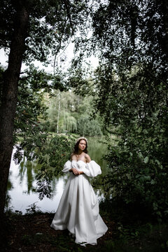 The bride in an elegant classic vintage dress in the park by the pond