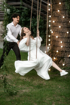 the groom rides a happy bride on a swing on the wedding day