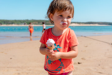 Little girl eating ice cream on summer beach 
