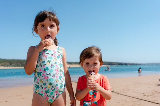 Little girls eating ice cream on summer beach 