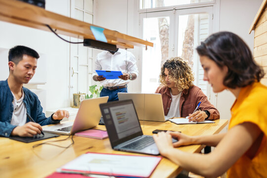 Young Colleagues Coworking With Laptop In The Office.