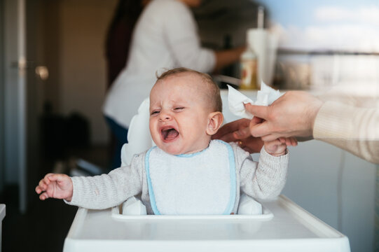 Crying baby sitting in high chair