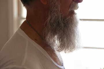 Man grooming his beard in the bathroom mirror.