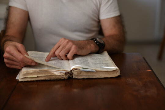 Man reading the bible at kitchen table.