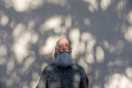 Man lenaing on wall enjoying sunshine.