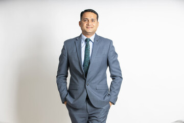Portrait of a confident young indian business man in a suit looking at camera isolated on white...
