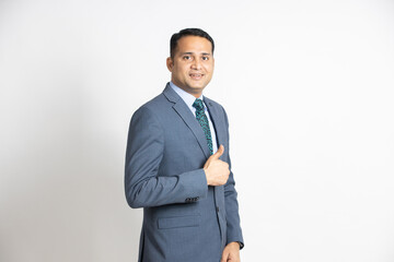Obraz na płótnie Canvas Portrait of a confident young indian business man in a suit do thumbs up isolated on white background. successful asian smiling male ceo of company standing, executive manager.