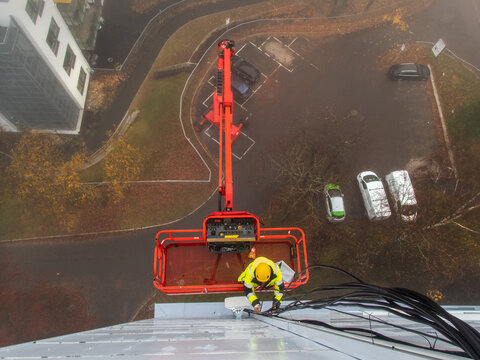 5G network installation, technicians work on a building using the lift