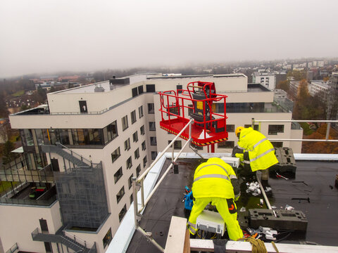 5G network installation, technicians work on a building using the lift