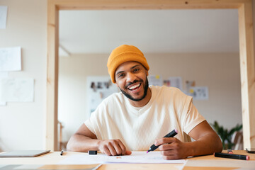 Smiling black male illustrator drawing on paper