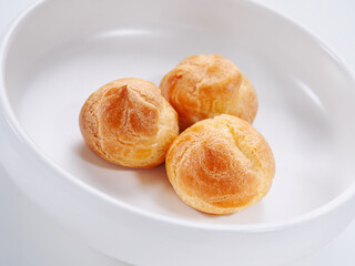 Bright fresh tasty profiteroles on a white plate. Close-up. Selective focus. Horizontal. High key. White background