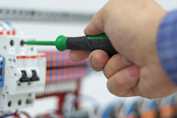 Mounting screwdriver in the hand of an electrical engineer close-up.