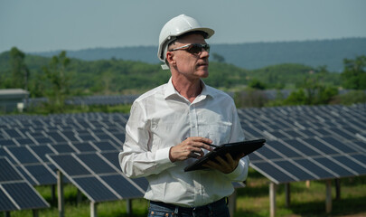 Obraz premium Concept: Renewable Energy. Team of engineers working to check the system through the phone. Photovoltaic for clean energy production. Innovate green energy for life on solar farms