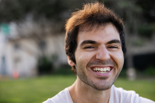 Expressive portrait of young man sitting in the park.