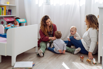 Mothers with kids enjoying motherhood in bedroom