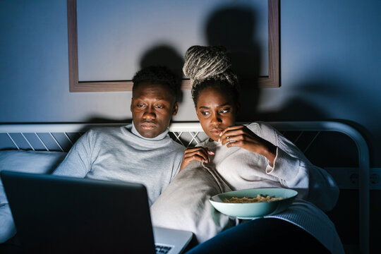 African American couple eating popcorn during showtime