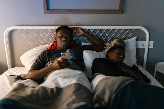 Man using smartphone near sleeping girlfriend