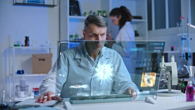 Lab scientist looking at virus hologram on computer screen, writing test data