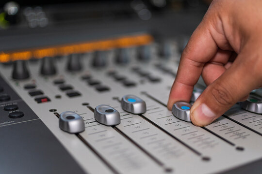 closeup of male hand moving a blue button from an audio console 