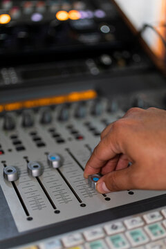 Male right hand moving buttons from an audio console 