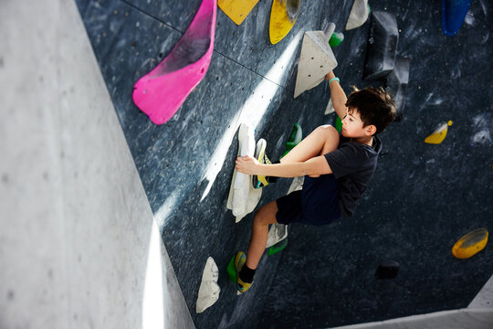 Boy climbing on a wall in bouldering gym