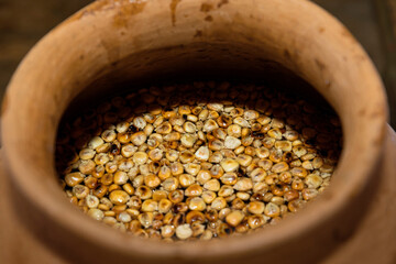 Clay pot with roasted yellow corn kernels and water