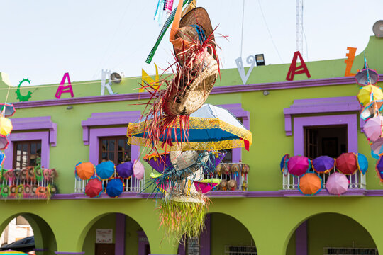 Hats and umbrellas hung for carnival in front of a colorful building