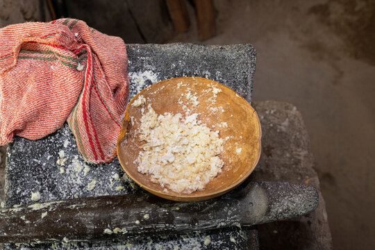 Jicara with white corn dough on a stone metate 