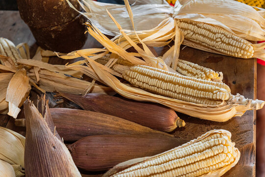White corns with their leaves on a wooden table 