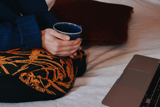 woman with a cup of tea watching laptop