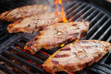 Barbecue Lammrückensteaks gegrillt als close-up auf einem Holzkohlegrill mit Feuer