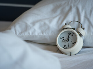 Retro white alarm clock On the white mattress in the bedroom