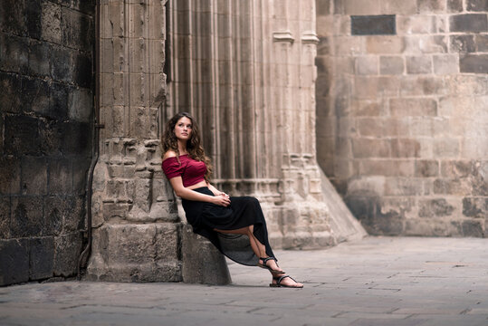 Stylish beautiful woman sitting on medieval street