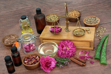 Herbs and flowers for natural plant based skin treatment with brass weighing scales and essential...