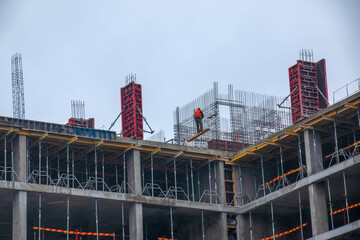 A worker prepares formwork for a modern metal-concrete structure of a residential building.